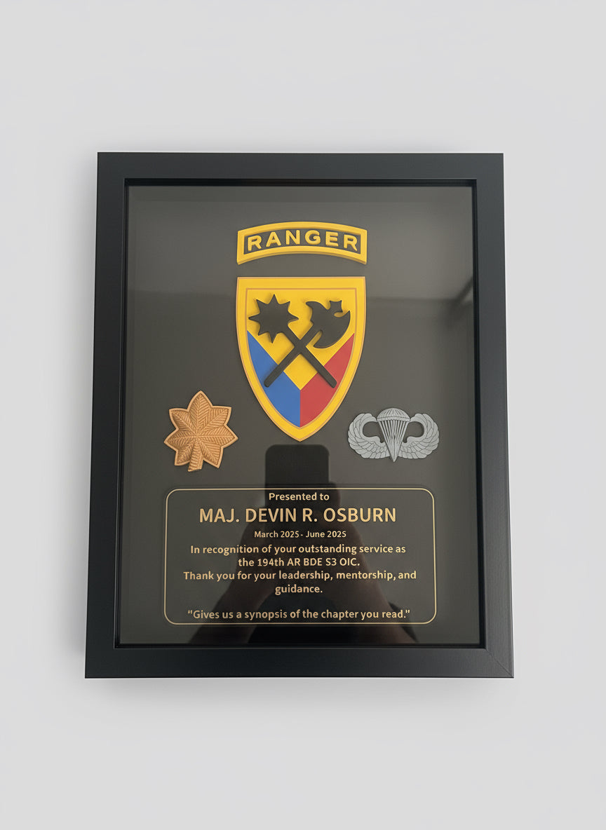 Framed military plaque with insignia and text, held by a hand.