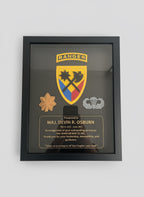 Framed military plaque with insignia and text, held by a hand.