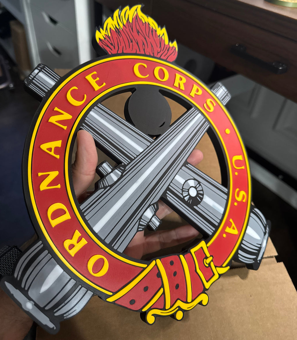 Close-up of a hand holding a metallic object with a 'U.S.A. Ordnance Corps' emblem.