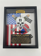 Framed military-themed display with a skull and crossbones design on an American flag background.