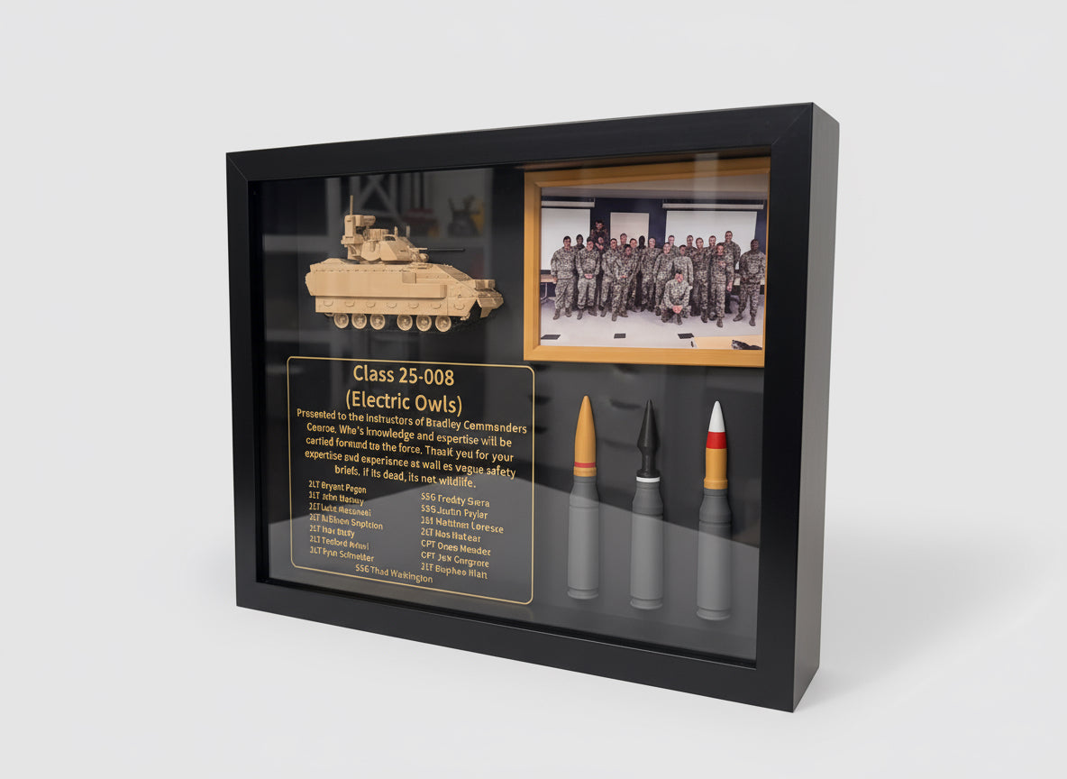 Framed display with a model tank, bullet, and photo of soldiers on a white surface.