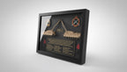 Framed military-themed display with tank models and text on a desk.