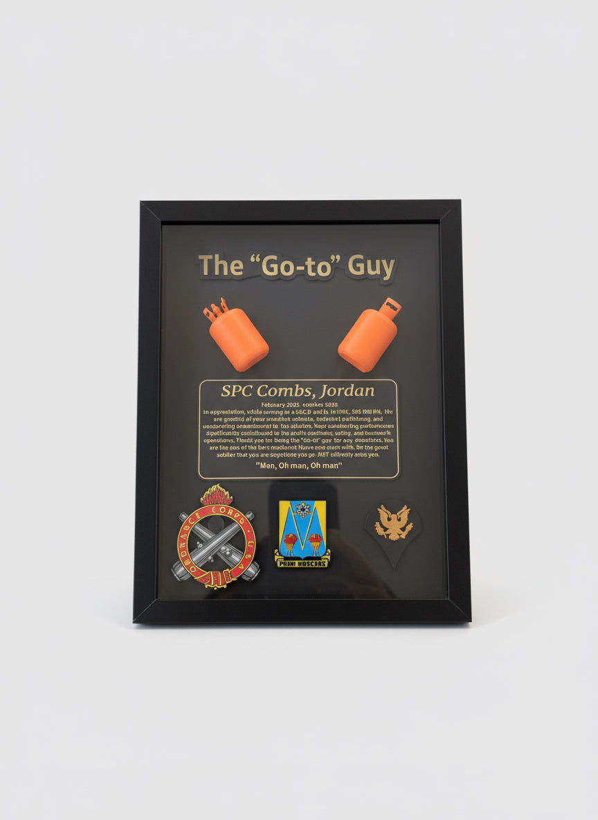 Framed recognition plaque with military insignia and text held by a person.